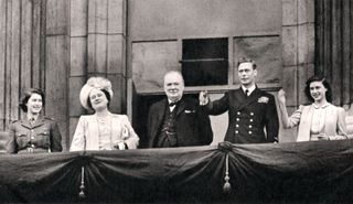 Queen Elizabeth, the Queen Mother, Winston Churchill, King George VI and Princess Margaret smiling and waving on the balcony of Buckingham Palace on VE Day 1945.