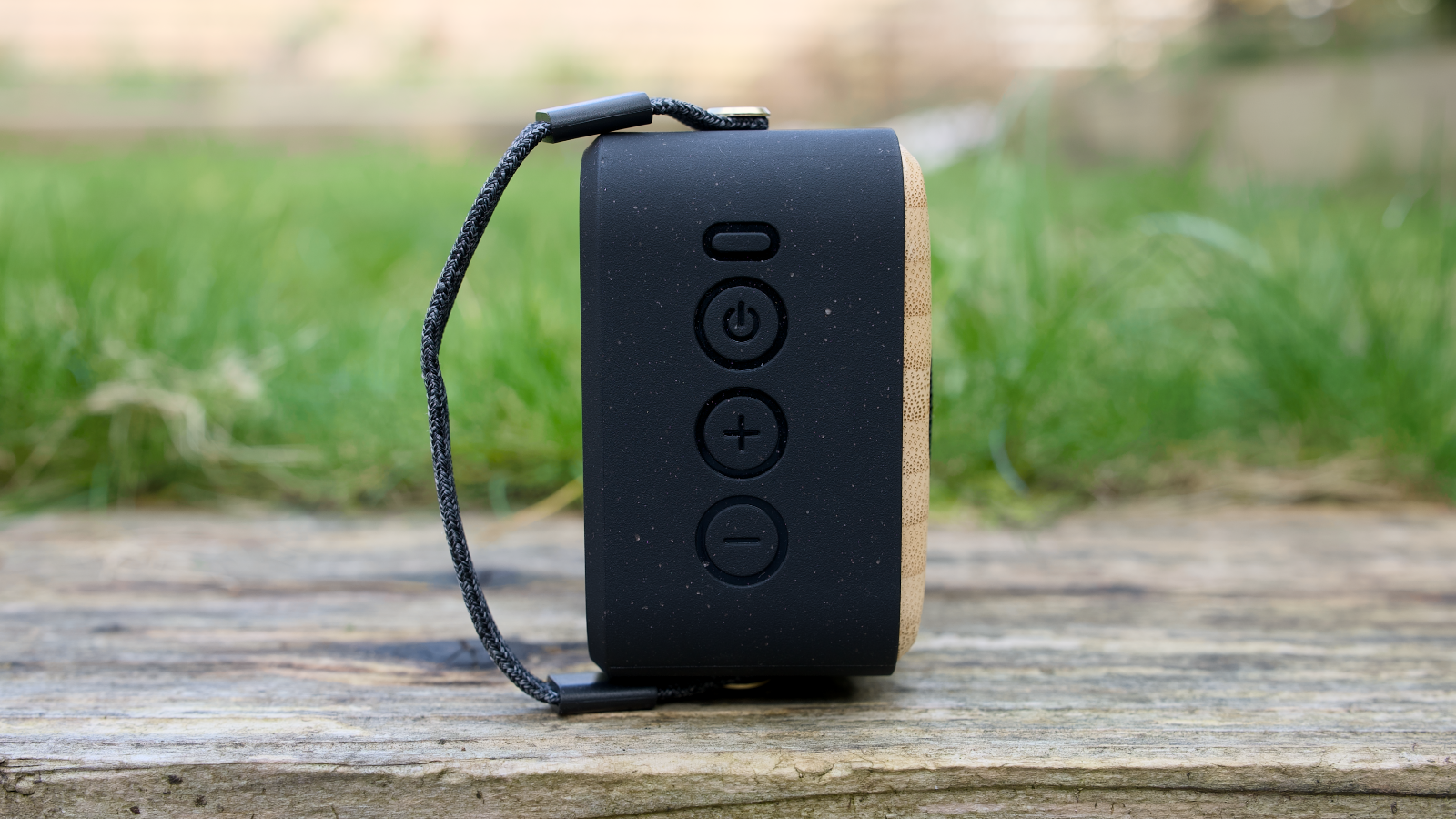 House of Marley Roots Solar Bluetooth speaker outdoors in a garden, on a wooden bench.