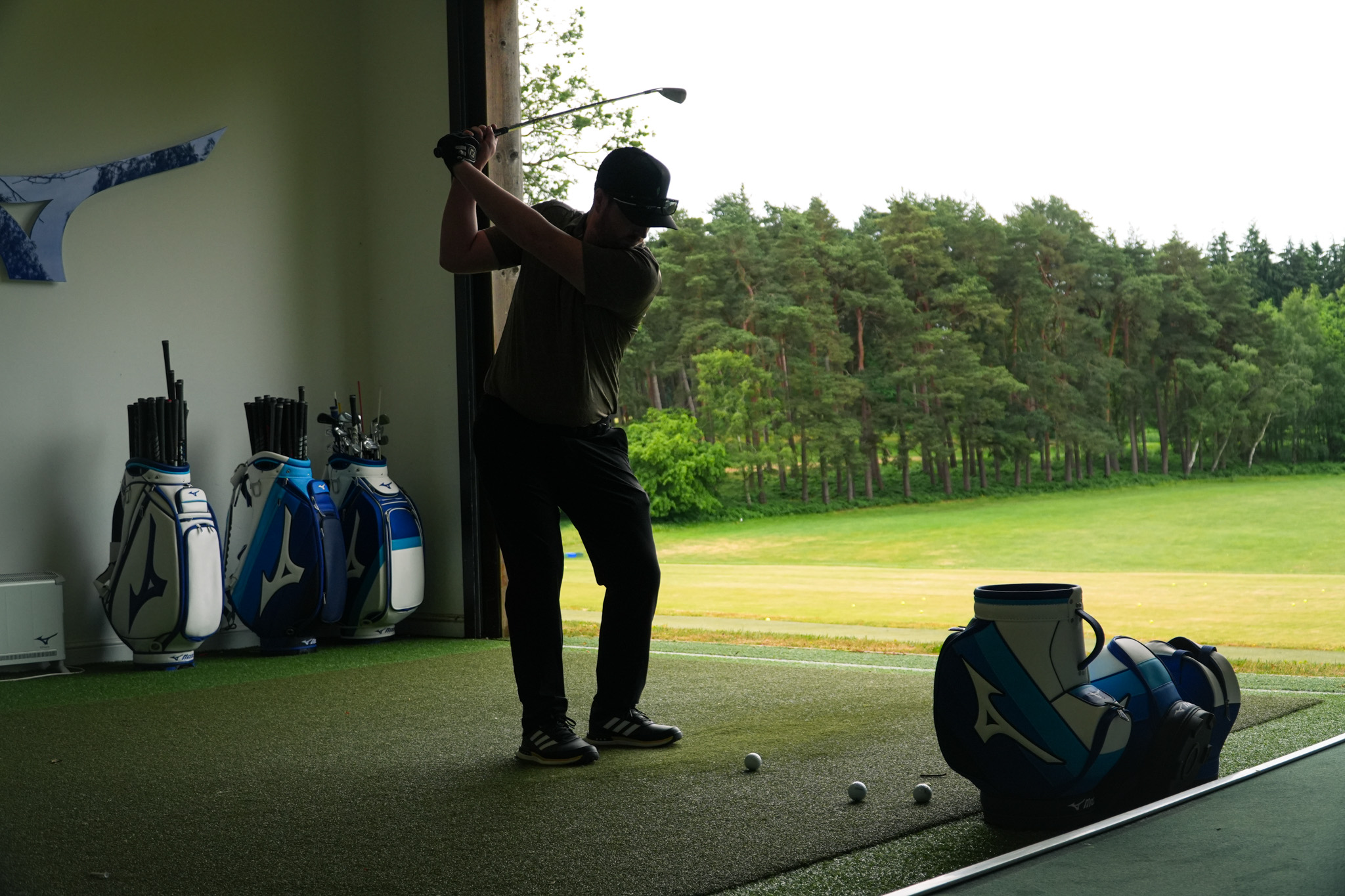 A golfer at the top of their backswing on an iron shot in a Mizuno hitting studio