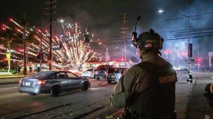 A Los Angeles County sheriff watches fireworks explode during anti-ICE protests in Paramount, California, on June 7, 2025.