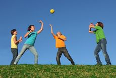 Four children play with a ball outside.
