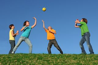 Four children play with a ball outside.