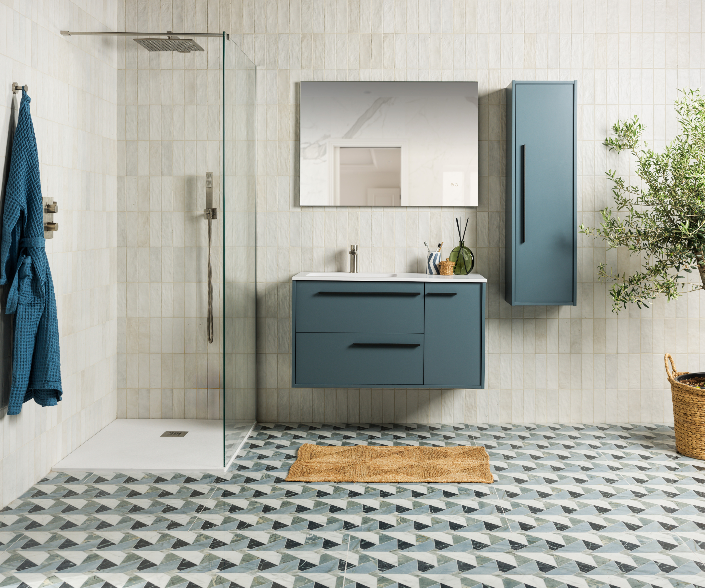 bathroom with blue geometric floor tiles, walk in shower, blue vanity and storage, off white wall tiles