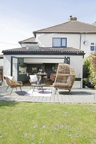 Bifold doors leading to a grey decked area with rattan outdoor living furniture