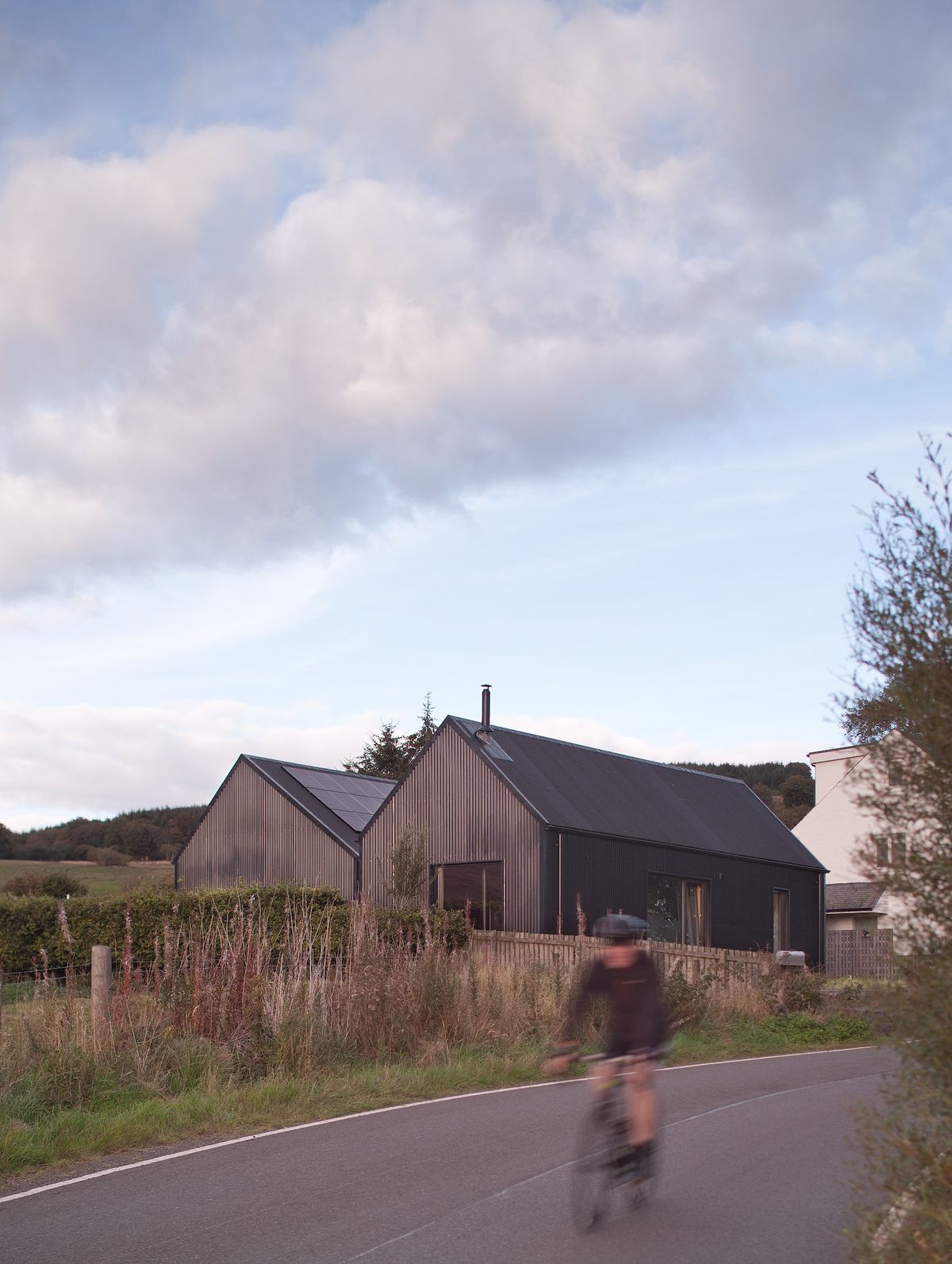 The exterior of a two volumed home with timber and metal cladding and solar pv