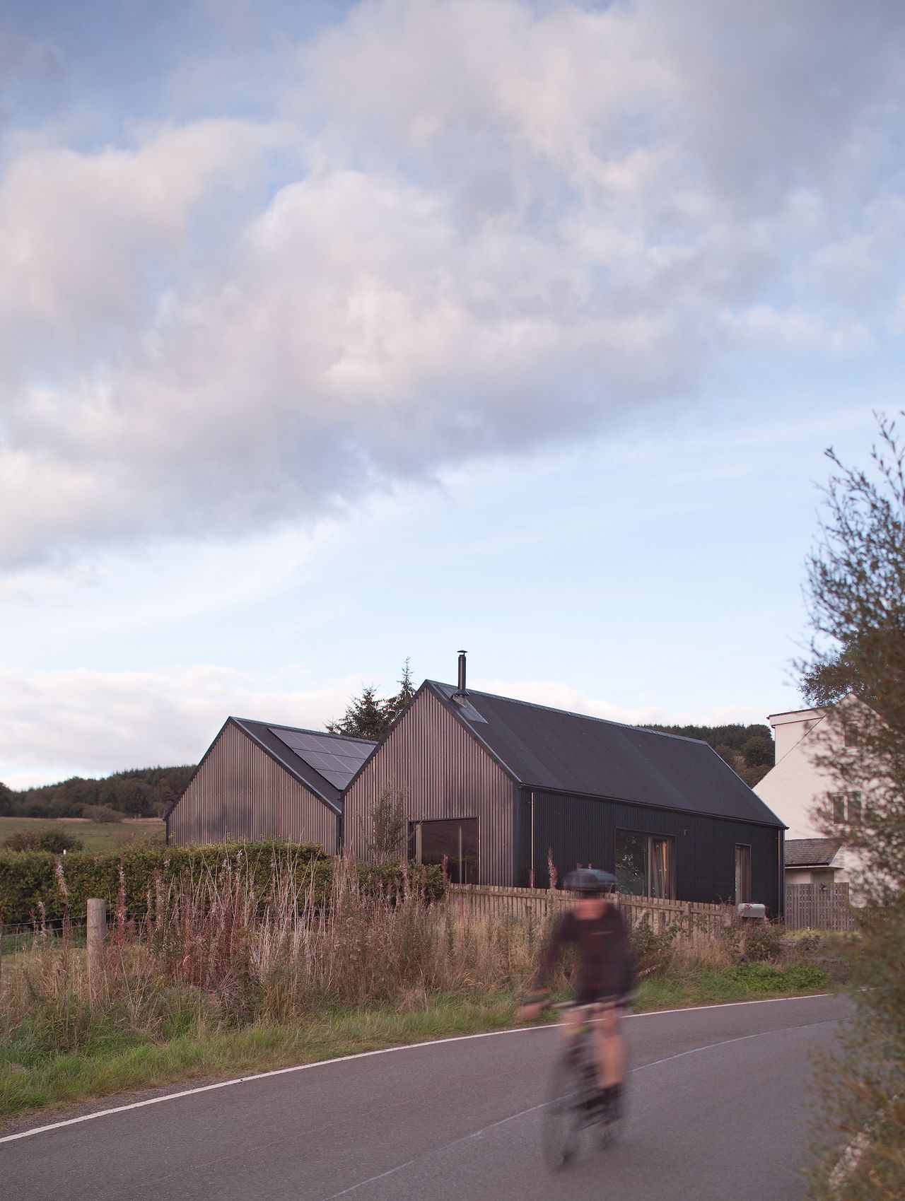 The exterior of a two volumed home with timber and metal cladding and solar pv