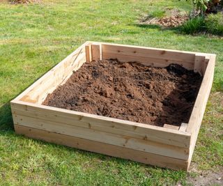 A raised garden bed being filled with soil