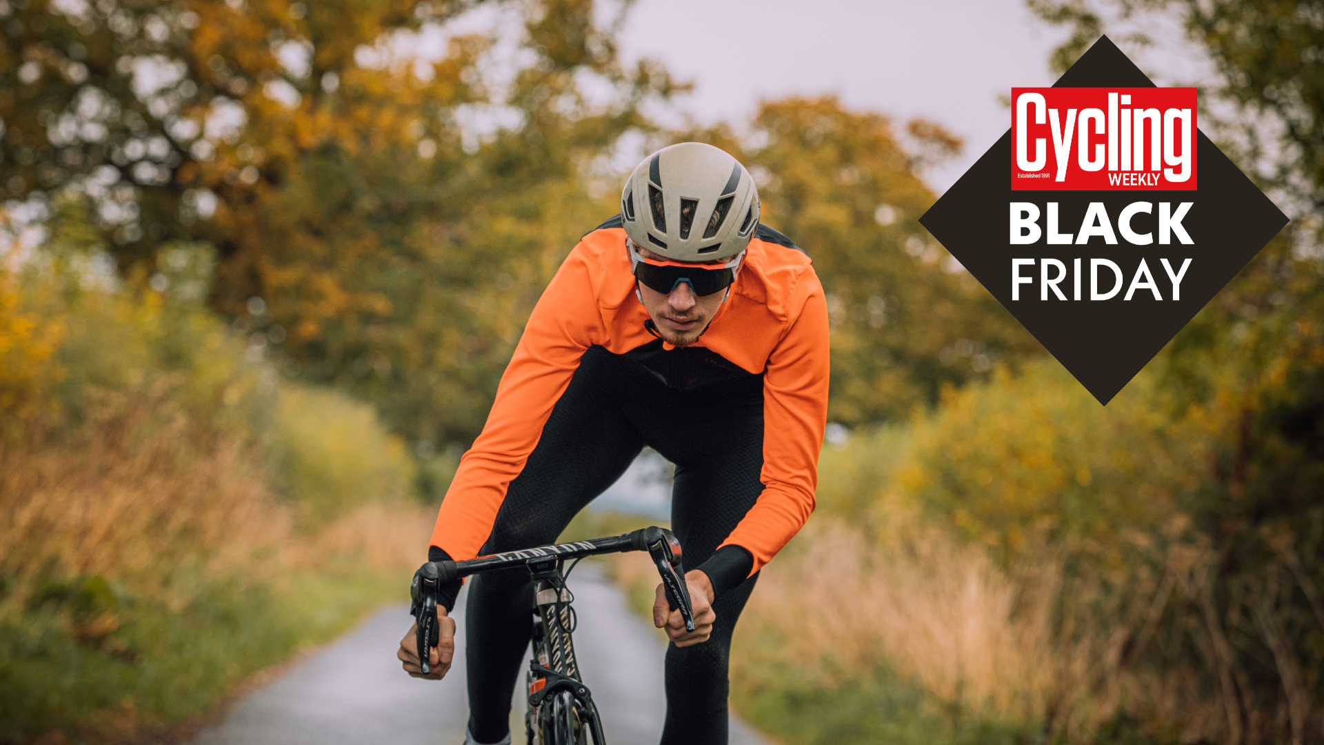 Image shows cyclist in an orange jacket racing towards the best Black Friday bikesdeals