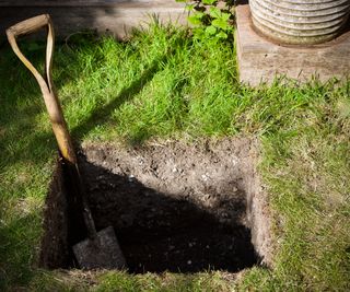 A hole dug in a lawn ready for soakaway crates to be installed