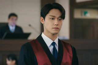 a man in a prosecutor's robe (Lee Do-hyun) stands in a courtroom with a judge behind him, in Netflix k-drama 'The Good Bad Mother'