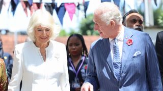Queen Camilla smiles as she and King Charles III arrive for their separate engagements inside Eastlands Library