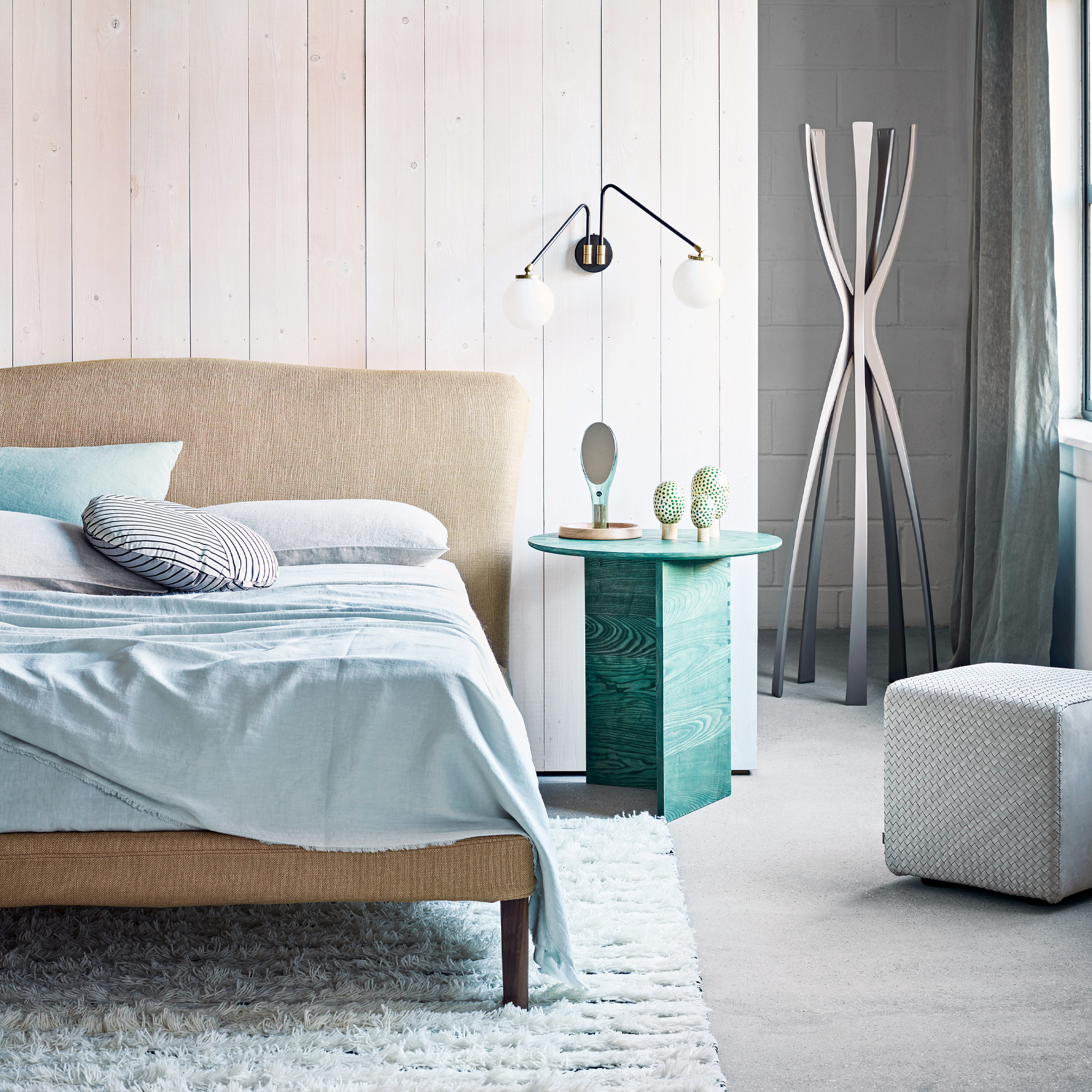 A bedroom with an upholstered bed and green bedside table