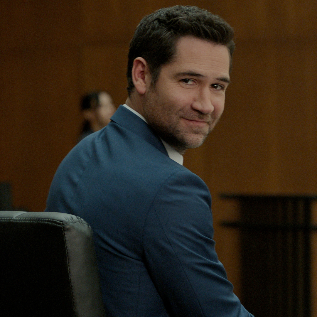 manuel garcia rulfo as mickey haller turning over his shoulder to look at the crowd in a court room in a still from the lincoln lawyer season 4