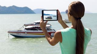 Woman using iPad to take photo of a boat