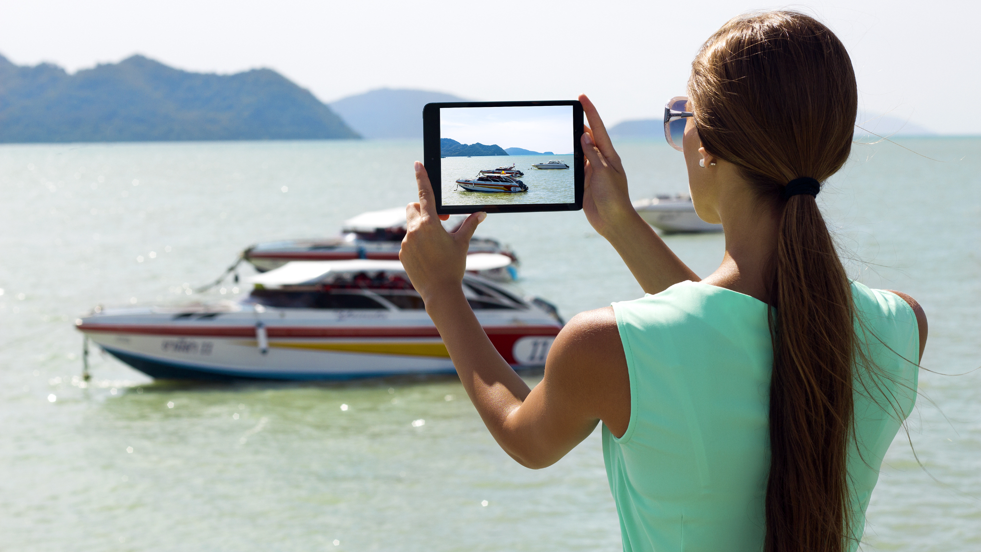 Woman using iPad to take a photo of a boat