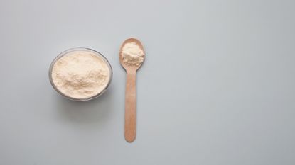 flat lay of powder in pot with spoon next to pot 