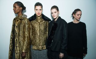 four female models, two wearing gold coats and two wearing black coats