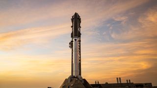 A towering SpaceX Starship rocket stands ready for Flight 13 launch amid a stunning pink sky in twilight.