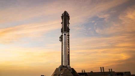 A towering SpaceX Starship rocket stands ready for Flight 13 launch amid a stunning pink sky in twilight.