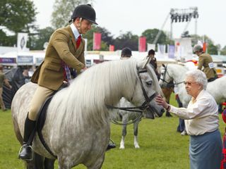 Queen Elizabeth II pats her horse 'Balmoral Erica' after it came second in the Ridden Mountain and Moorland Class on day 4 of the Royal Windsor Horse Show at Home Park on May 17, 2014