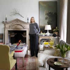 Cath Kidston by fireplace in living room of family home in Cotswolds