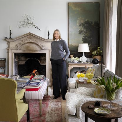 Cath Kidston by fireplace in living room of family home in Cotswolds