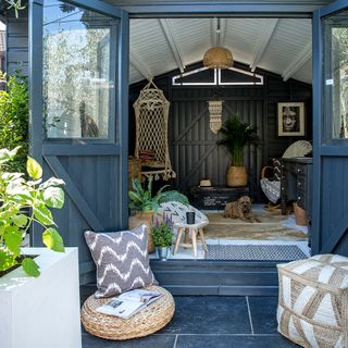 blue shed with cushion and potted plants