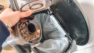 A vacuum dust cup being emptied into the trash