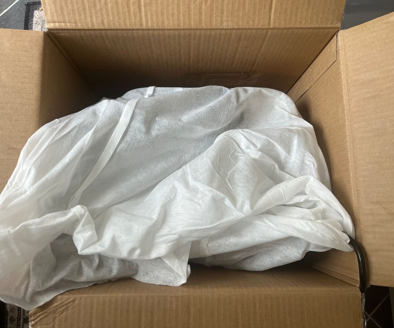 A top down view of the inside of the box for the Ninja Luxe Caf&eacute; mini espresso machine showing a white fabric bag.
