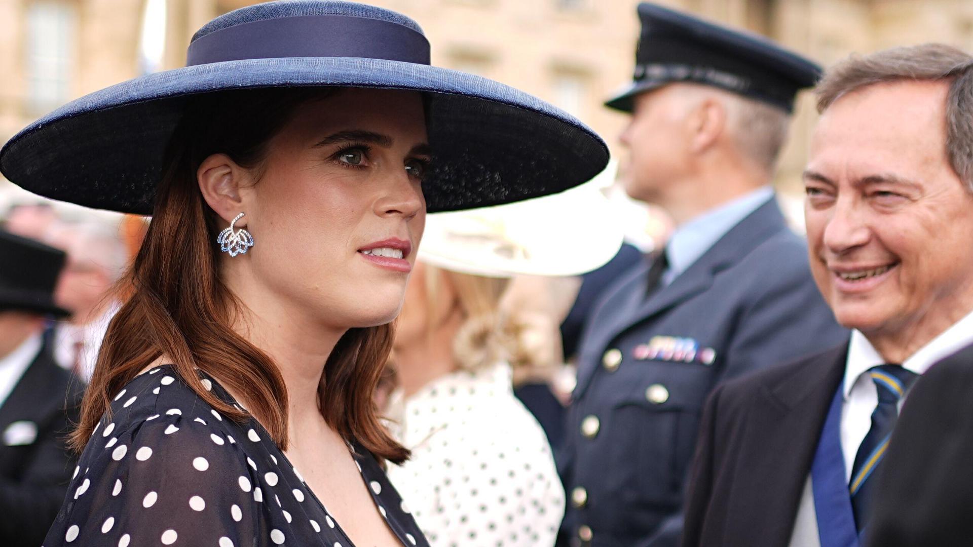Princess Eugenie wearing a navy dress and hat
