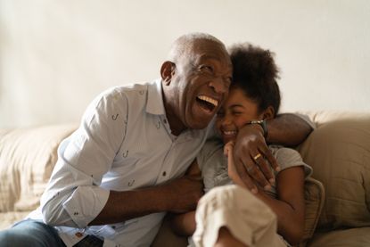 A grandfather hugs his granddaughter while laughing