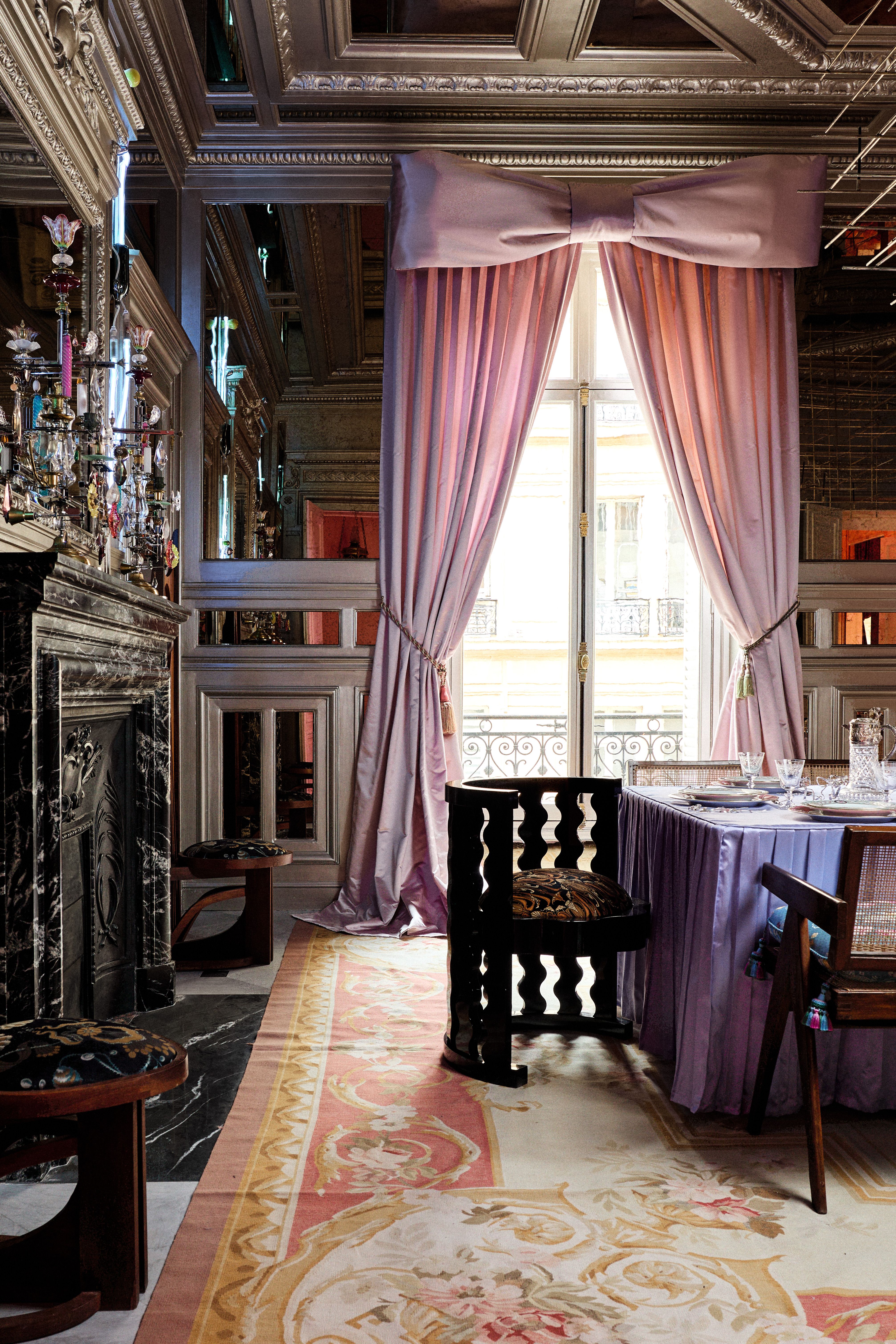 a large ornate dining room with huge pink curtains tied in a bow