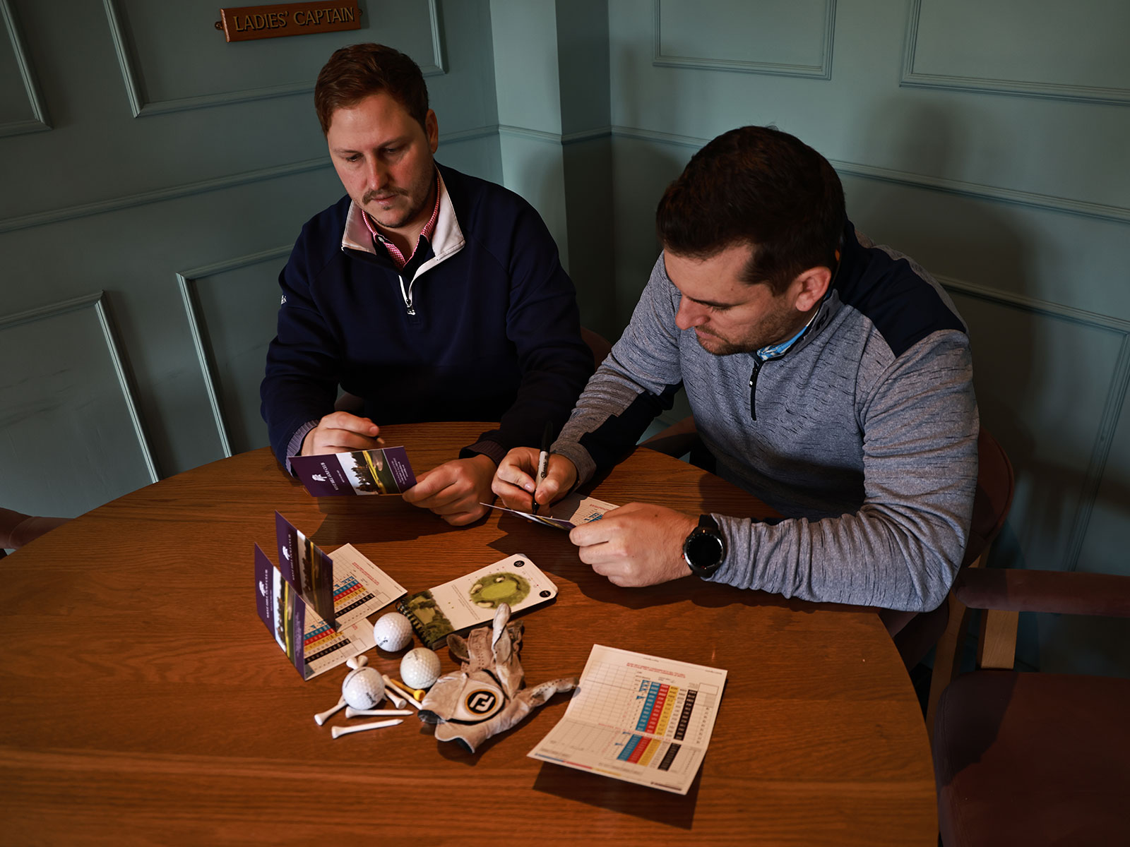 two golfers going over their scorecards in the clubhouse