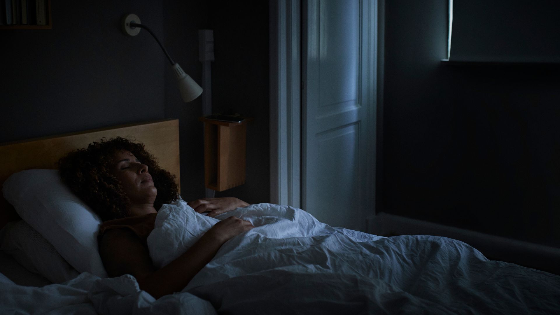 Woman lying asleep in a dark room at night.