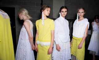 Yellow and white dress with lace and pompoms worn by models.