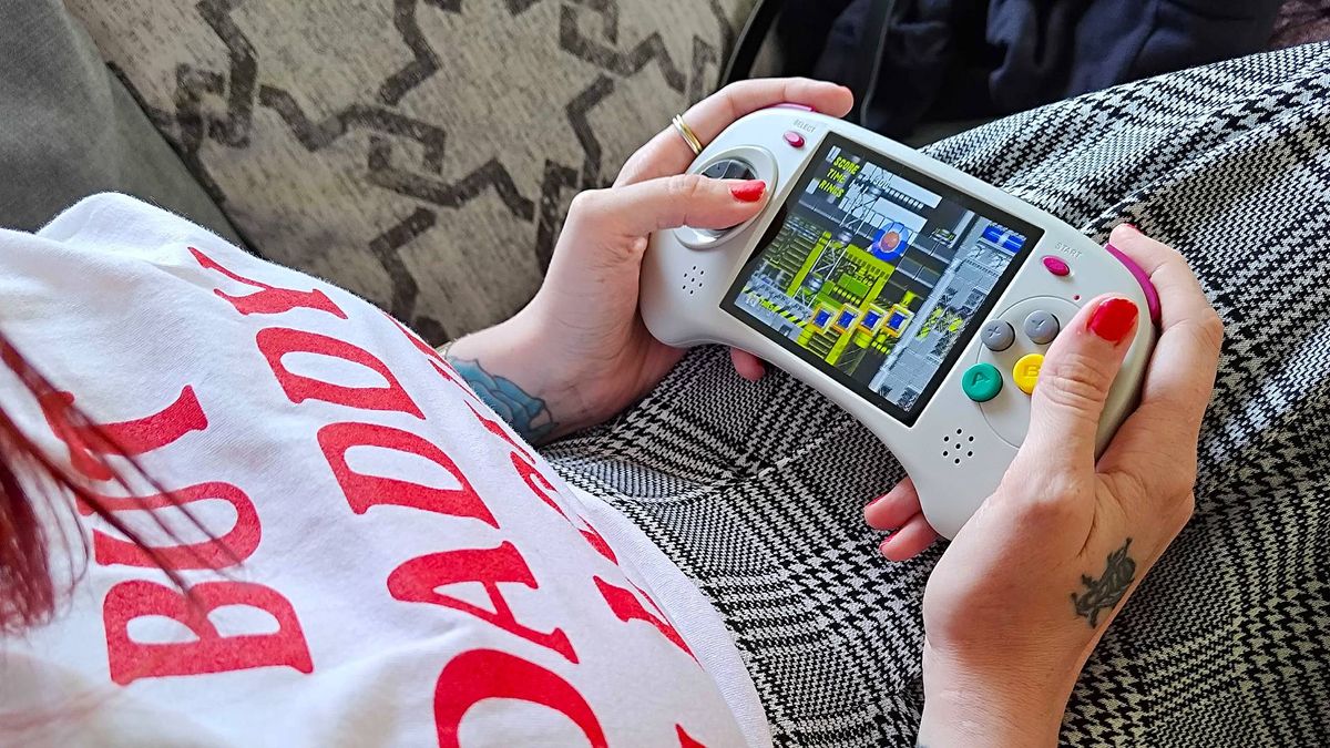 Hands holding Anbernic RG ARC-D with Sonic the Hedgehog 2 gameplay on screen.