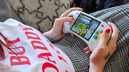 Hands holding Anbernic RG ARC-D with Sonic the Hedgehog 2 gameplay on screen.