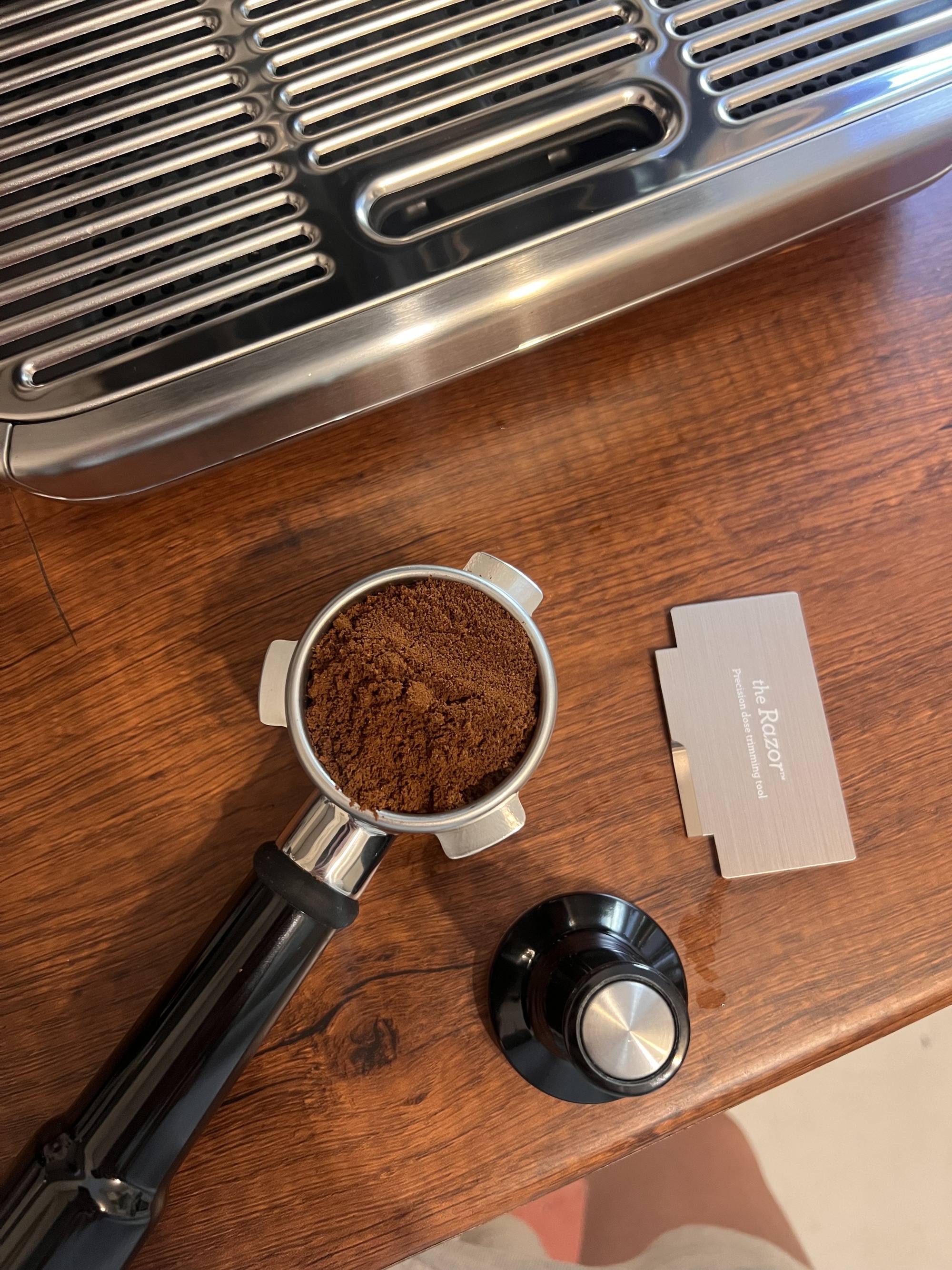 A black portafilter with grounds in it on a wooden countertop.