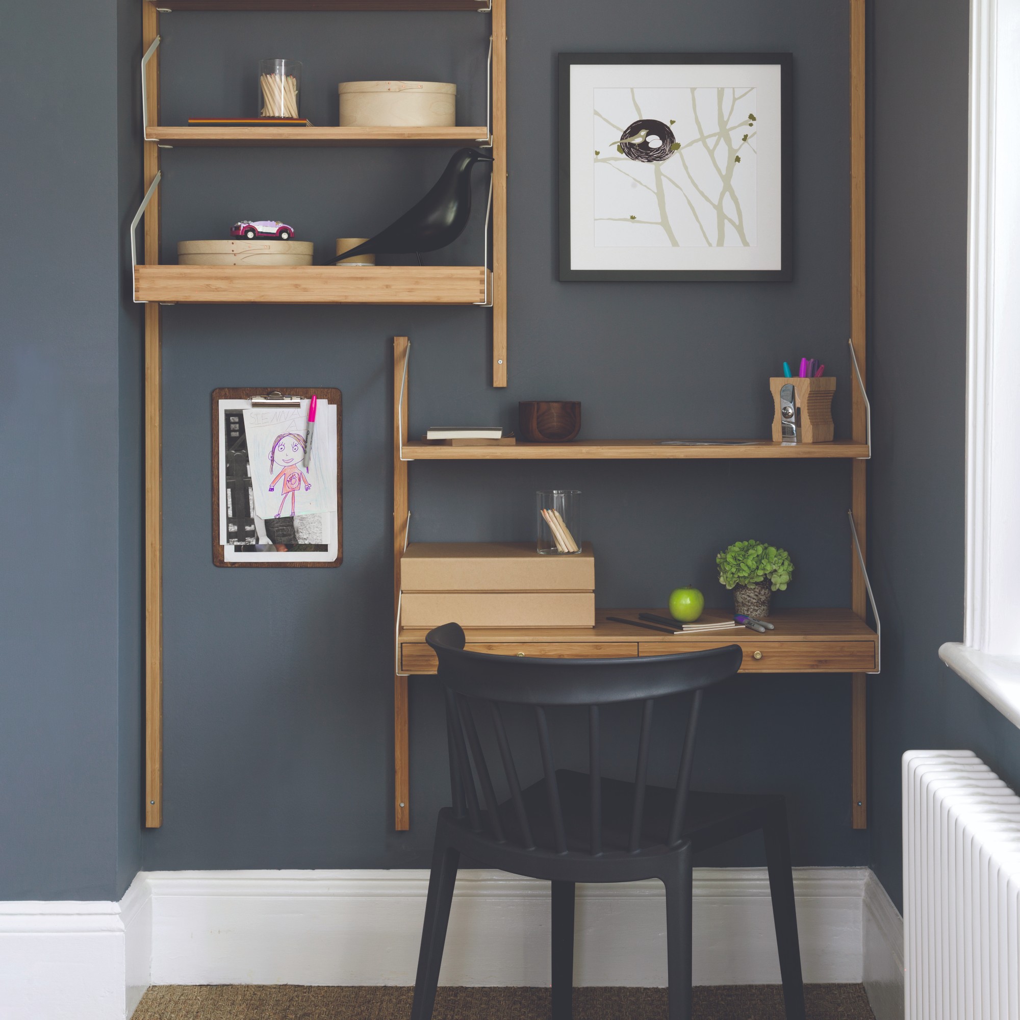 A dark painted home office with a desk and an art print