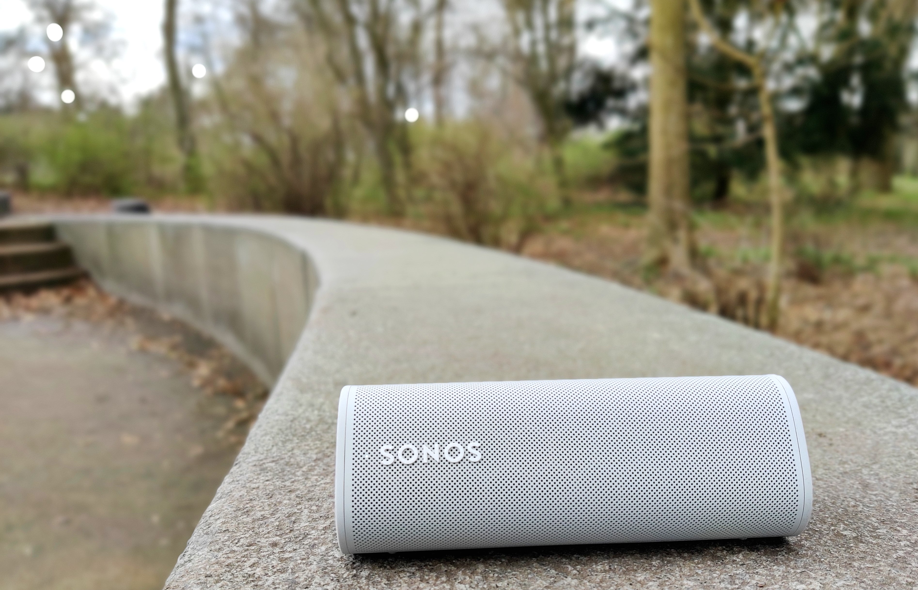 En vit Sonos Roam ligger utomhus på en betongmur.