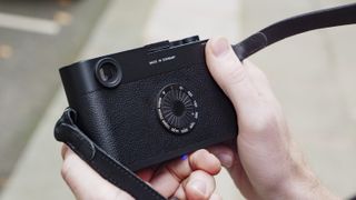 Leica M11-D camera in the hand, closeup of ISO dial on the rear