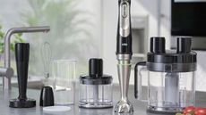 A Braun Multiquick 9 hand blender with all of its attachments spread out on a grey kitchen counter