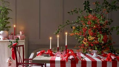 A table laid for Christmas with candles and a Christmas tree.
