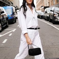 Woman in white shirt, white pants, and black accessories