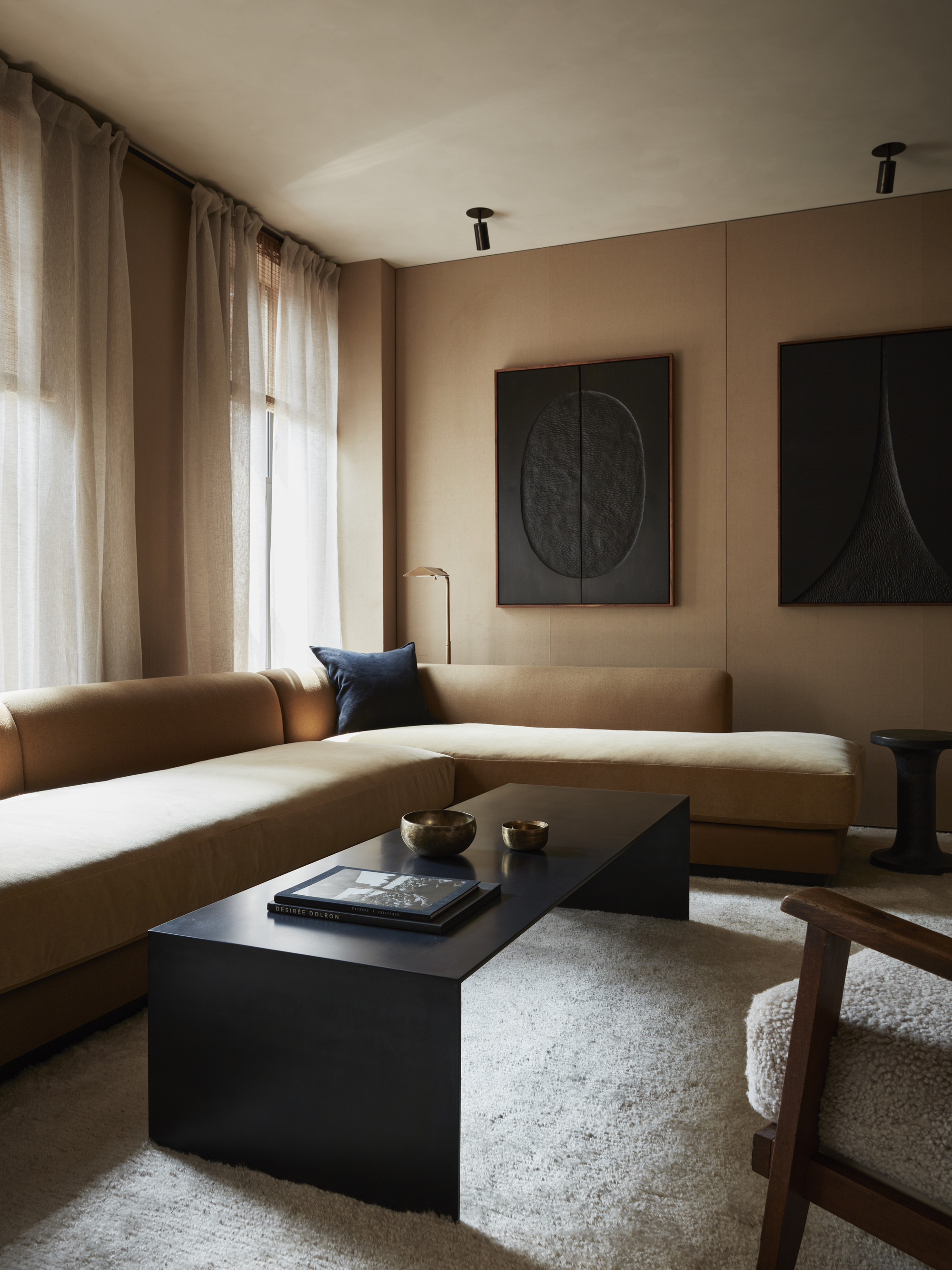 A large living room with tan colored walls and a tan sofa, plus a large black rectangular table