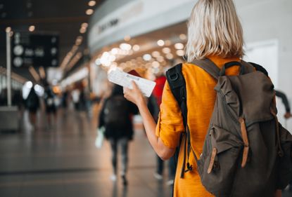 A woman at the airport holding a passport with a boarding pass