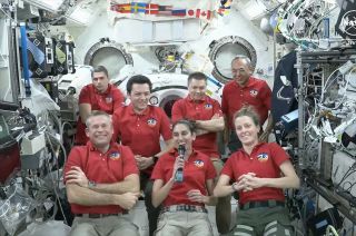 seven people in red shirts aboard the international space station.