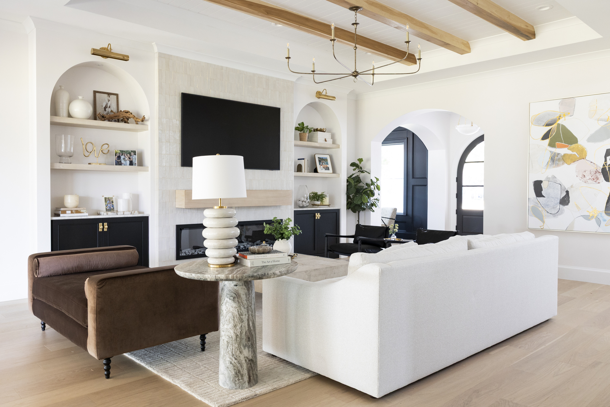 A modern coastal living room with a fireplace flanked by alcove shelves and a white sofa in the middle of the room next to a brown chaise
