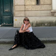 Woman wearing a full black skirt and flat shoes