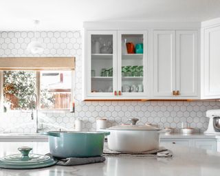 A white kitchen with casserole dishes and sink by window